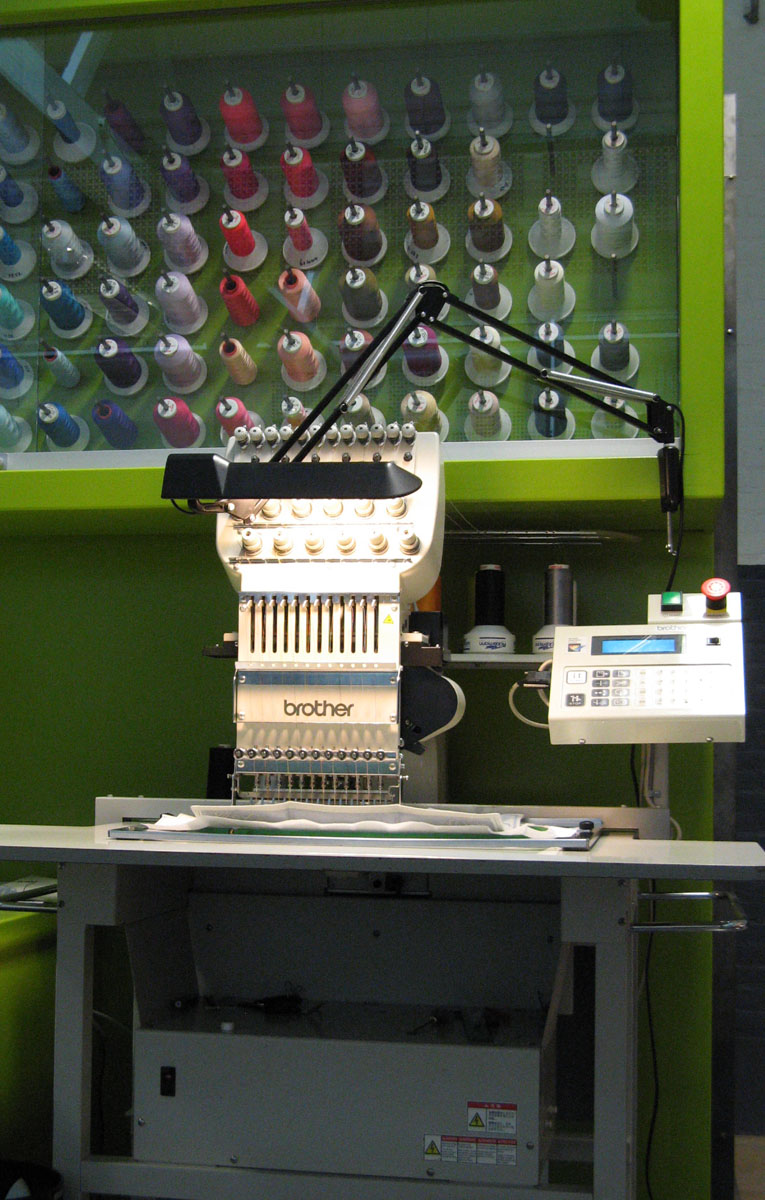 Brother single-head industrial embroidery machine in a shop with thread wall