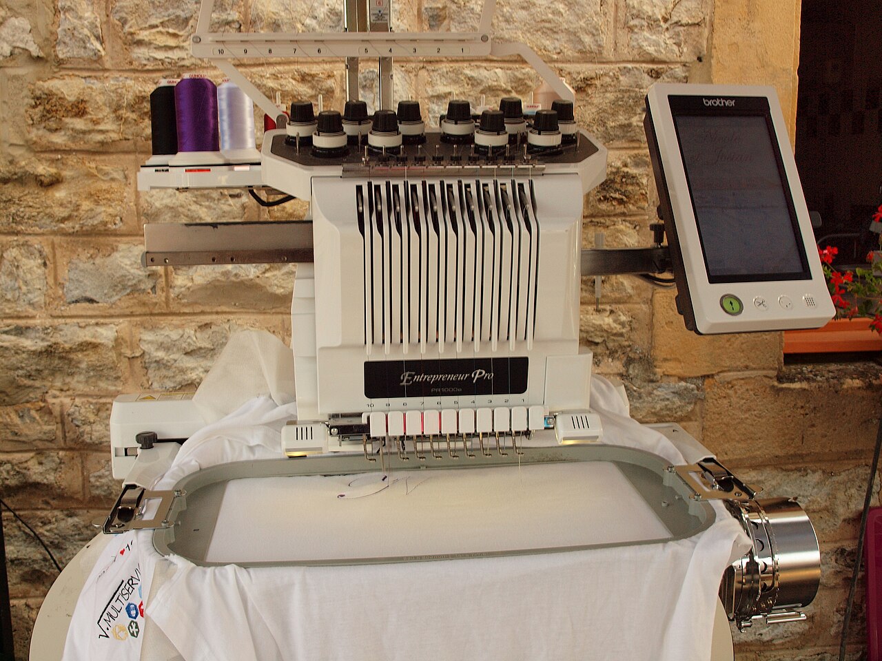 Front of a Brother 10-needle embroidery machine with thread cones and hoop