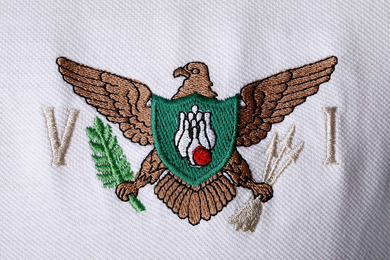 Machine-embroidered eagle logo with green shield on white pique fabric