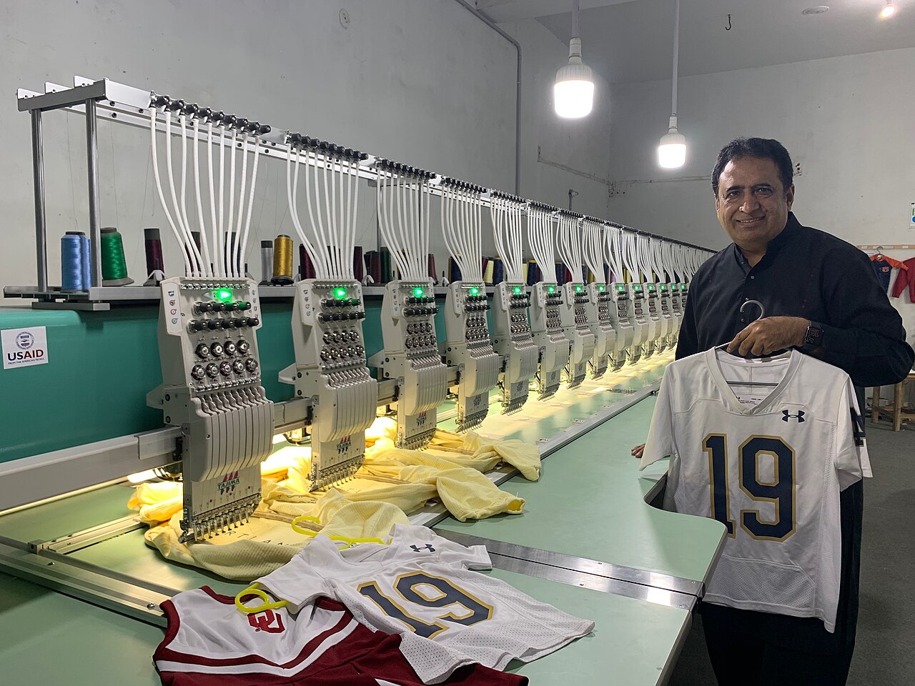 Long multi-head embroidery machine with many heads and thread cones above each head