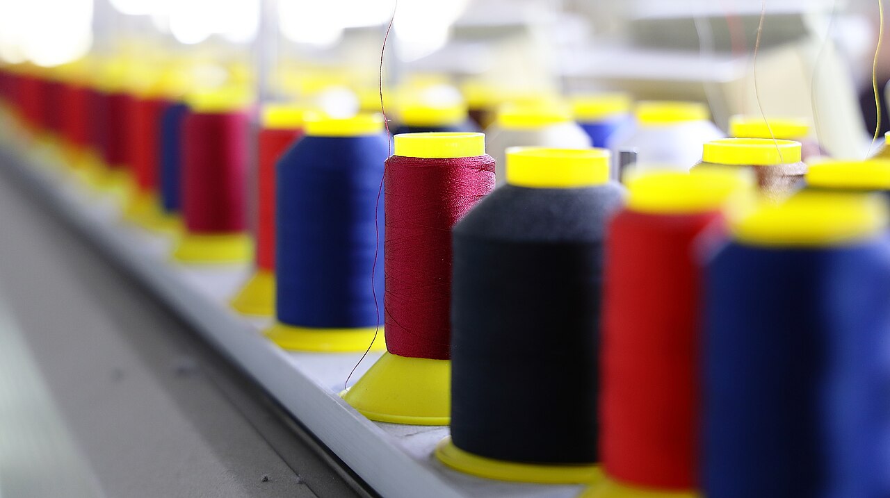 Close-up of red, blue and black thread cones on an embroidery machine thread stand