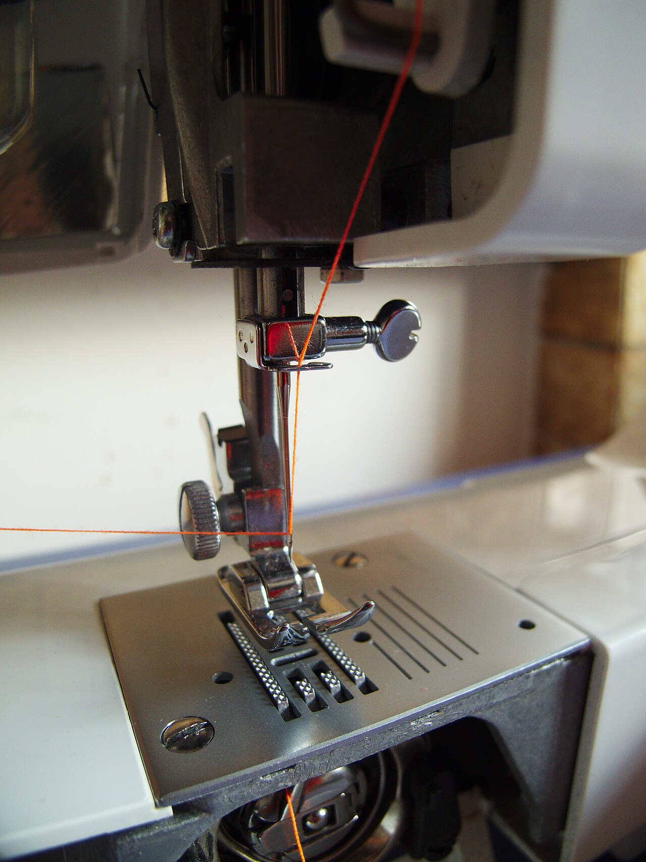 Sewing machine needle, presser foot and needle plate with orange thread