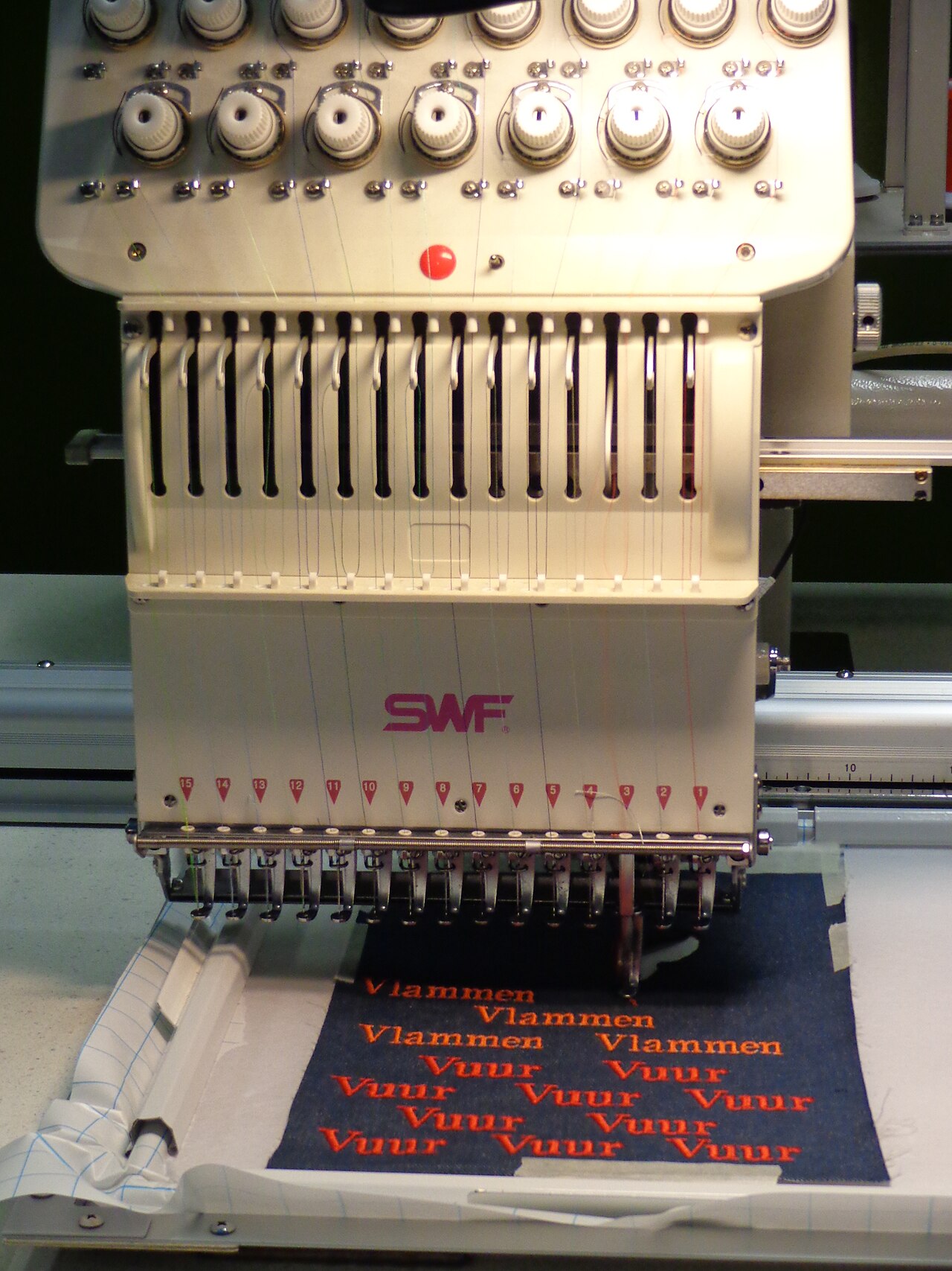 Close-up of the needle case on an SWF embroidery machine sewing red lettering